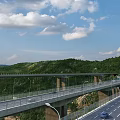 Scenic Mountain Highway Bridge With Tunnel And Forested Surroundings Under Blue Sky