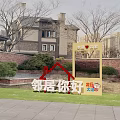 Neighborhood Welcome Sign at Community Entrance with Residential Buildings and Green Landscape
