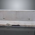 Gray Concrete Curb With Two Holes And Damaged Bottom On Reflective Surface