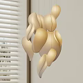 Modern Beige Chandelier With Curved Leaf Shaped Elements Hanging Against Light Colored Wall And Window Blinds