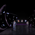 Futuristic Exhibition Space With Curved Structures People Purple Lighting And Artworks