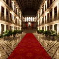 Grand Architectural Interior With Red Carpet Columns Symmetric Plants And High Ceiling