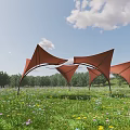Red Tensile Membrane Structures In Green Meadow With Blue Sky And Trees