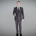 A Man In Dark Suit Standing Against Gray Background With Right Hand Extended For Greeting