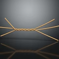 Crossed Wooden Sticks With Twine Wrapped Center On Reflective Dark Surface