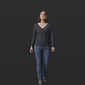 A Woman Standing Against Black Background Wearing Dark Gray V Neck Sweater And Blue Jeans