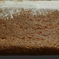 Brown Bundt Cake With White Frosting And Crumbled Toppings On Top