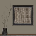 Woven Square Artwork With Dark Frame And Gray Vase With Twigs On Light Wall