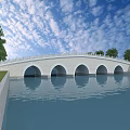 Stone Arch Bridge Over Calm Water With Trees Blue Sky And White Clouds