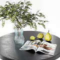 Glass Vase With Green Leafy Plants On Black Table With Yellow Pears And Open Magazine