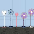 Stylish Pedestal Fans in Various Colors Standing Against Light Wall on Marble Floor