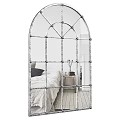 Arched Iron Frame Mirror in Bedroom Reflecting Bed Nightstand and Wooden Floor