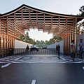 Wooden Roofed Entrance Gate With Trees People Bicycle And Green Car