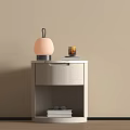 Modern Light Gray Bedside Table With Drawer Open Shelf And Pink Lamp Glass Cup Books