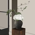 Gray Ceramic Vase Holding White Hydrangeas And Green Branches Against White Wall With Curtain