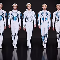 Group of Men in White and Blue Futuristic Outfits Walking on Black Runway