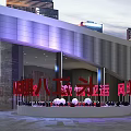 Modern Building Exterior With Purple Lighting And Red Signage In City Plaza