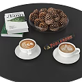 Black Round Coffee Table With Two Coffee Cups White Saucers Books And Pinecone Bowl