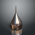 Copper Colored Textured Weapon with Conical Shape Wide Base and Pointed Top on Reflective Surface