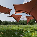 Red Tensile Membrane Structures In Green Meadow With Blue Sky And Trees