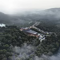 Modern Hotel Building in Lush Forest Surrounded by Mountainous Landscape and Lake with Misty Atmosphere