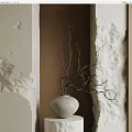 Gray Vase With Twigs On White Pedestal Against Beige And Brown Textured Walls