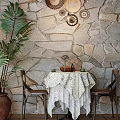 Dining Table Set with White Lace Tablecloth Brown Chairs Palm Plant Stone Wall Decorative Plates