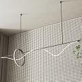 Modern Linear Pendant Light With Circular Ring Design Above Perforated Wall And Green Plant