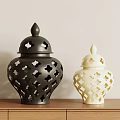 Decorative Black And Cream Vases With Cutout Patterns On Wooden Tabletop Against Light Wall