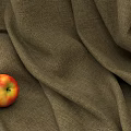 Red Yellow Apple Placed On Brown Textured Fabric With Soft Folds