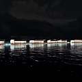 Row Of Lit Water Buildings At Night With Mountain Backdrop And Reflections