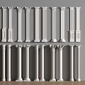 White Decorative Columns With Various Designs Displayed Against Gray Wall And Wooden Floor