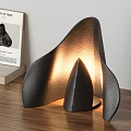 Modern Black Table Lamp with Curved Leaf Shade and Cone Base Emitting Warm Glow