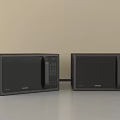 Two Black Samsung Microwaves Side by Side on Gray Countertop with Beige Kitchen Wall