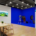 Professional Studio Setup With Blue Backdrop Camera Tripod Two People Lighting And TV Screens
