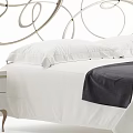 Elegant Double Bed With Curved Metal Headboard White Bedding Dark Blanket And Bedside Tables