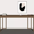 Brown Wooden Desk With Stack of Books and Framed Monochrome Abstract Artwork Against White Wall