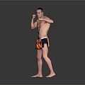 Shirtless Man Practicing Boxing Stance In Orange And Blue Shorts Against Gray Background