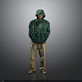 A Man Standing In Green Hooded Jacket Khaki Pants With Hands In Pockets Gray Background