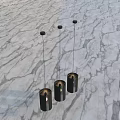 Three Modern Black Cylindrical Chandeliers Hanging In Interior With Marble Background