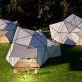 Modern Geometric Outdoor Tent In Grass Field With String Lights And Wooden Furniture