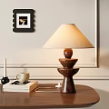 Wooden Base Table Lamp With Beige Fabric Shade On Table With Books Mug And Candle