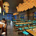 Modern Restaurant Interior With Hanging Chandeliers Blue Chairs And Wooden Tables
