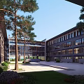 Modern School Building Exterior With Large Windows Trees Courtyard And Green Lawn