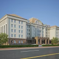 Office Building Exterior Design With Beige And Brown Facade Arched Windows Sloped Roof And Trees