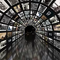 Tunnel of Screens Displaying Black and White Photos with Years and Person Walking