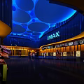 Modern Cinema Lobby With IMAX Sign And Shoppers Under Blue Lighting