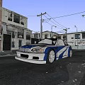 Blue and white modified car with large wheels parked in front of old factory building