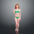 Woman with red hair wearing green bikini standing against gray background barefoot in natural pose
