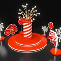 Art Installation Featuring Red And White Striped Cylinder With Firework Lights And Red Flower Decorations